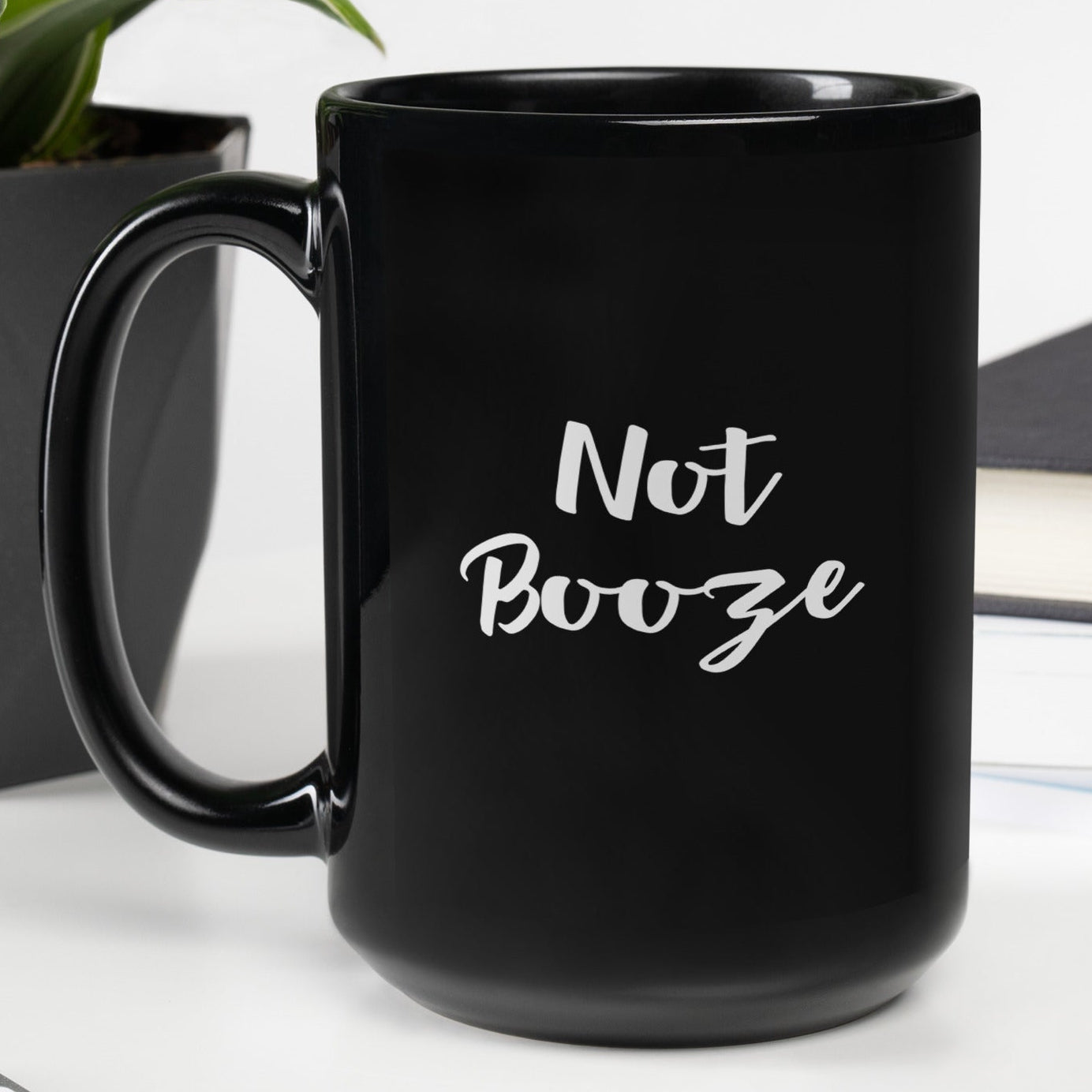 15 oz black glossy mug with handle on the left, featuring the Not Booze design, from wayward.biz.