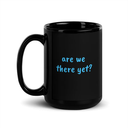15 oz black glossy ceramic mug with a handle on the left, featuring the "Are We There Yet" design by wayward.biz.